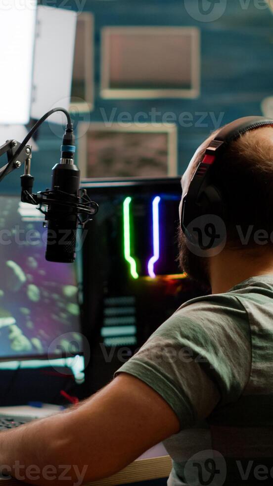Excited streamer with headphones winning important online esport competition of space shooter playing on powerful computer. Professional pro gamer streaming videogames using professional microphone and headset photo