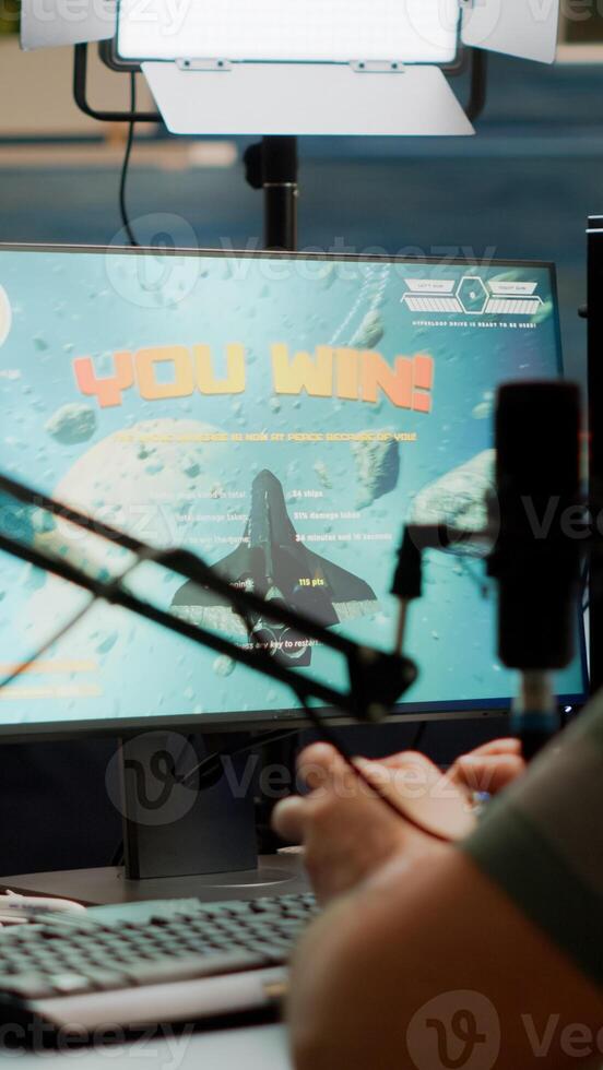 Entusiastic man gamer streamer wining space shooter games holding joystick playing on professional RGB keyboard and talking on stream chat. Pro cyber using microphone in gaming tournament photo