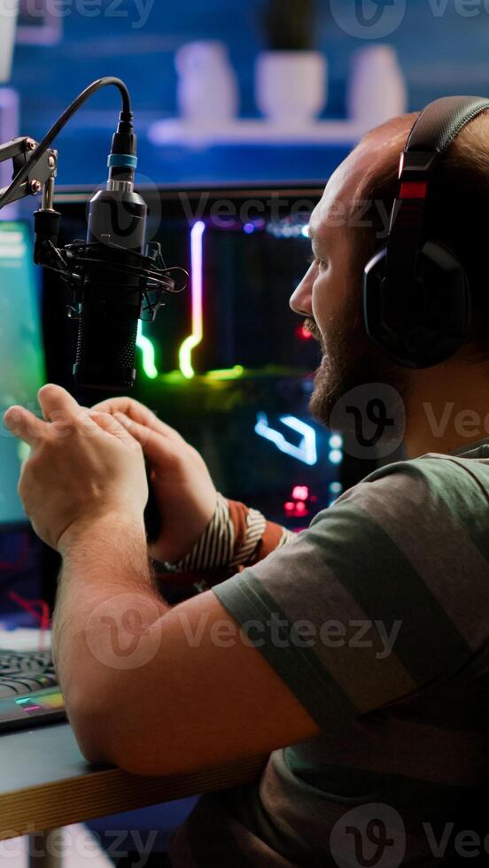 Concentrated gamer playing shooter game in gaming competition using wireless controller wearing professional headphones. Online streaming cyber performing during tournament using RGB powerful PC photo