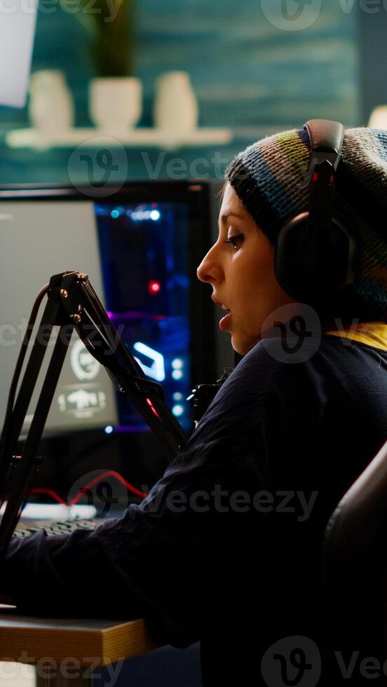 Focused streamer playing shooter game for virtual competition using professional headphones. Online streaming cyber performing during gaming tournament using powerful PC with RGB and stream open chat photo