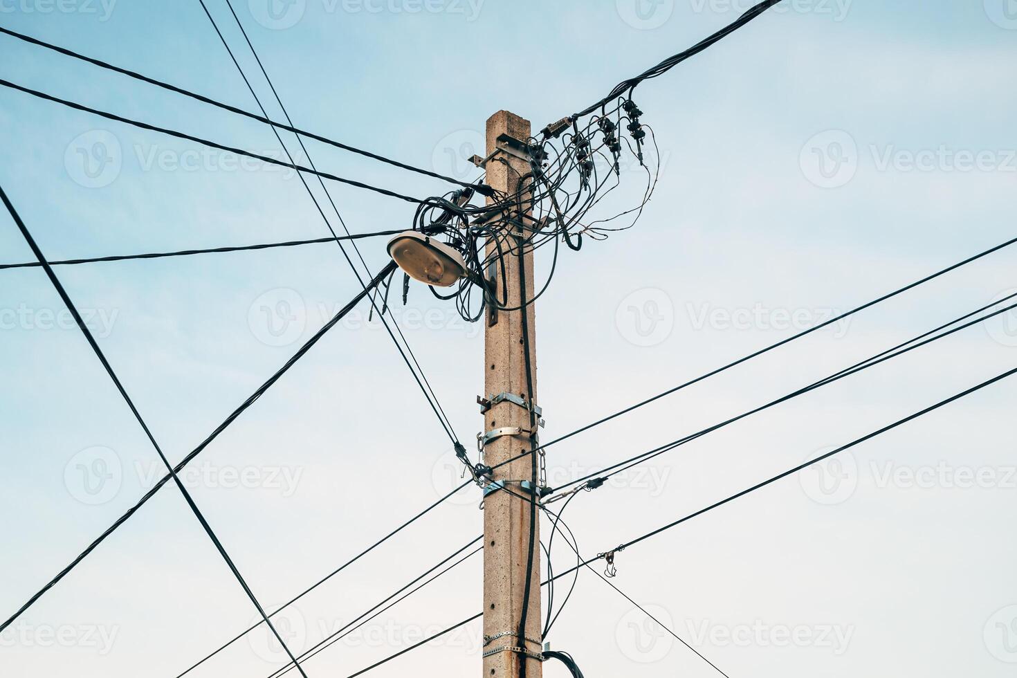Street light with electricity utility pole and messy electrical wires, low angle view photo