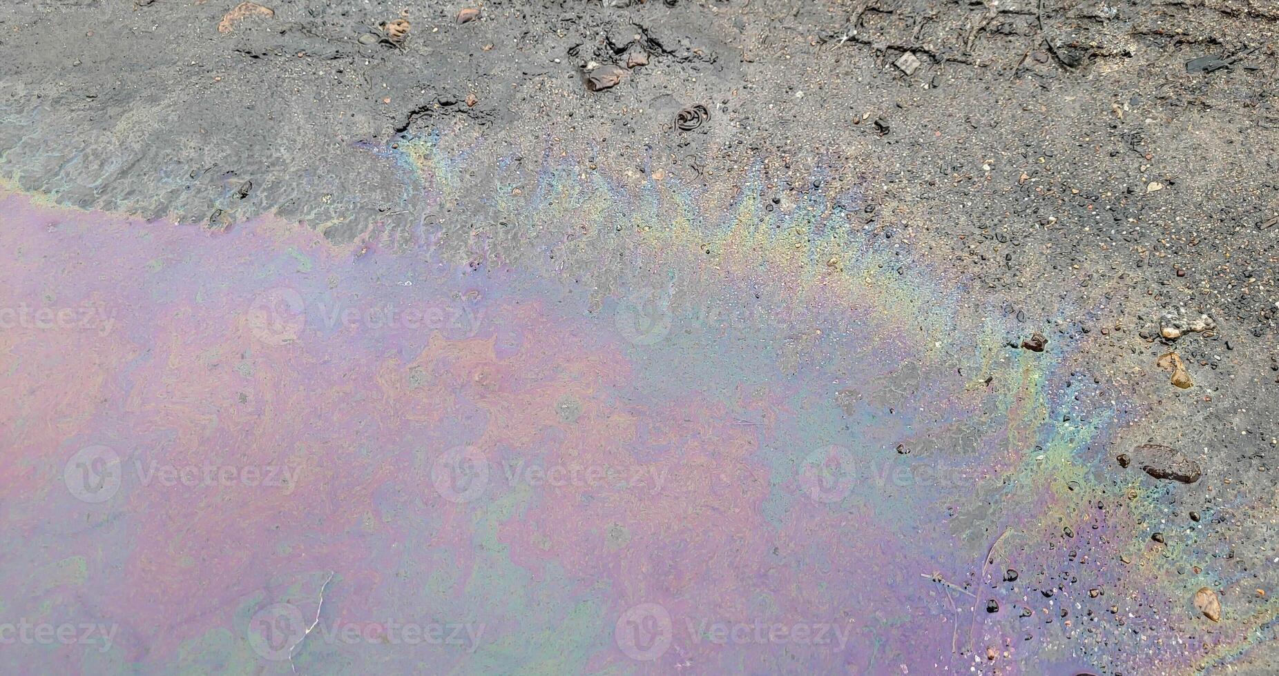 A large rainbow puddle of spilled petroleum product on the road. The concept of environmental pollution photo