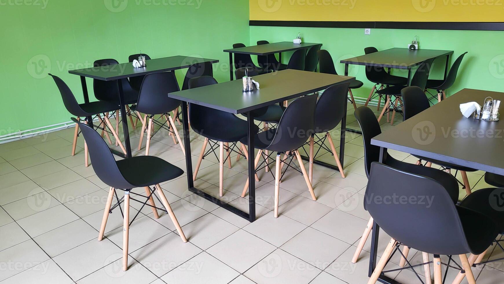 The cafe has light green walls and black tables and chairs. photo