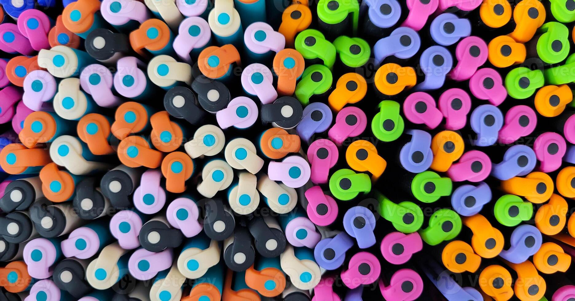 Abstract background of multicolored caps of plastic pens. A set of several liners, markers and colored markers of different colors, top view photo
