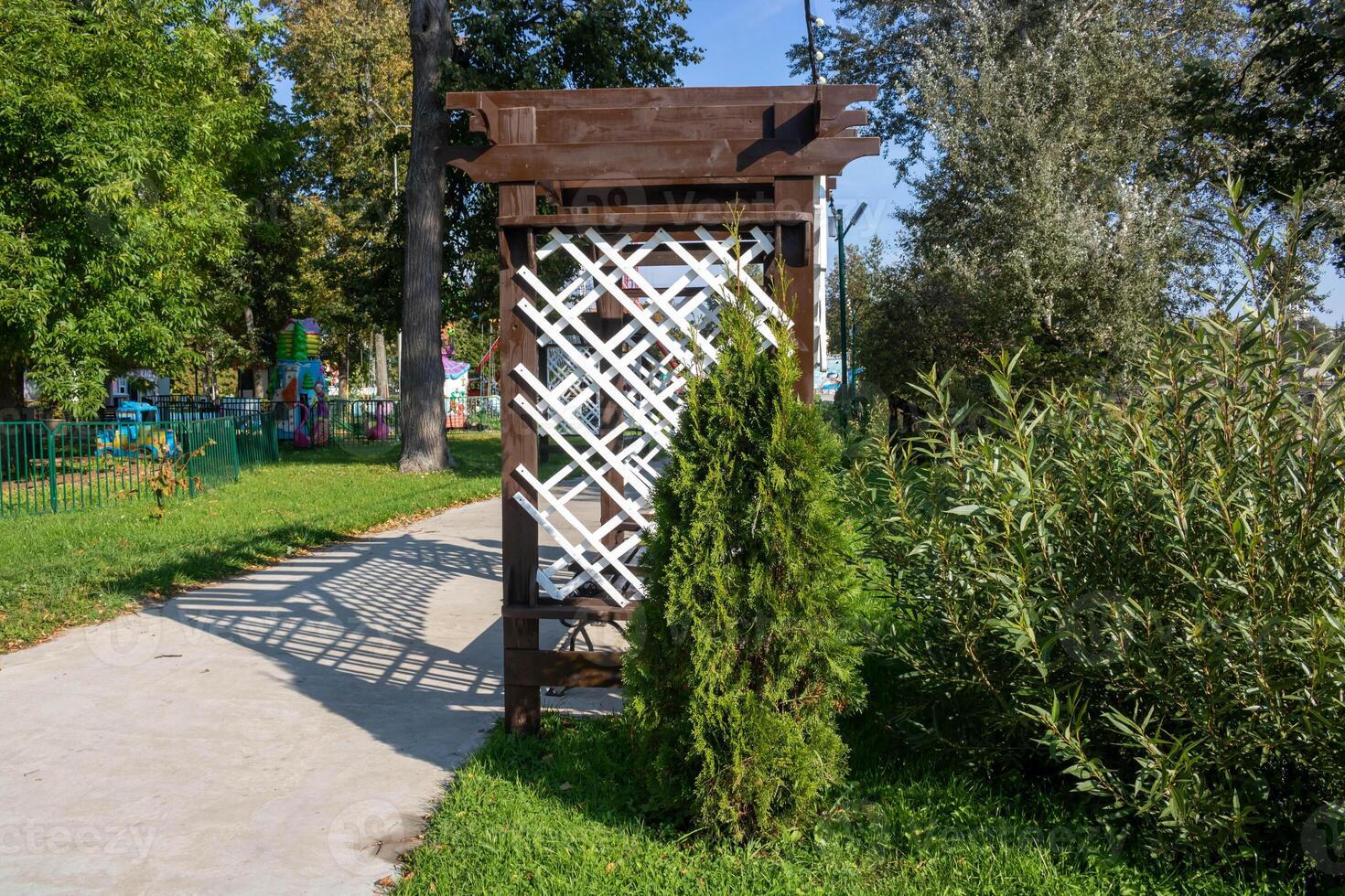 The interior of a brown wooden gazebo with a white openwork lattice. Cozy wooden gazebo in summer photo