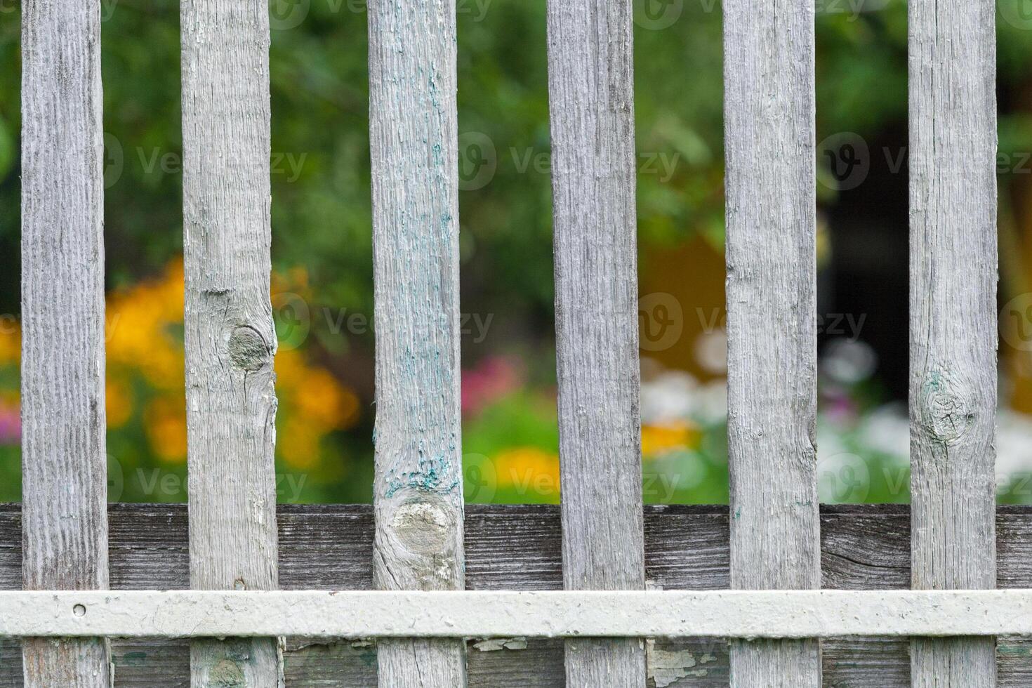 Fragment of a wooden fence painted white a background of garden in bokeh photo
