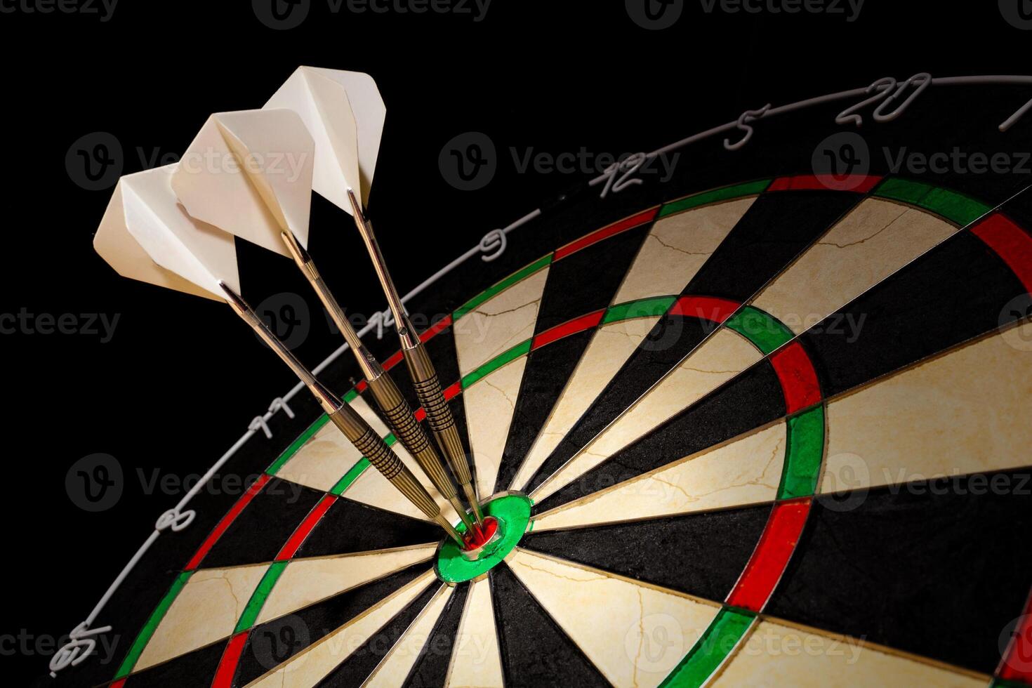 Sisal dartboard with three darts in a bullseye on a black background photo