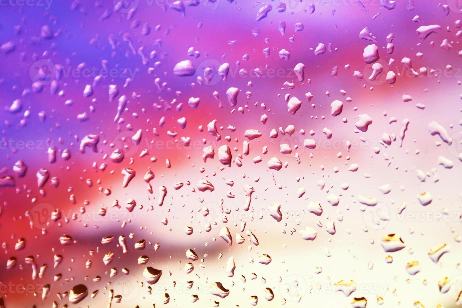 Rain drops on the window glass against the background of bright colored sunset clouds photo