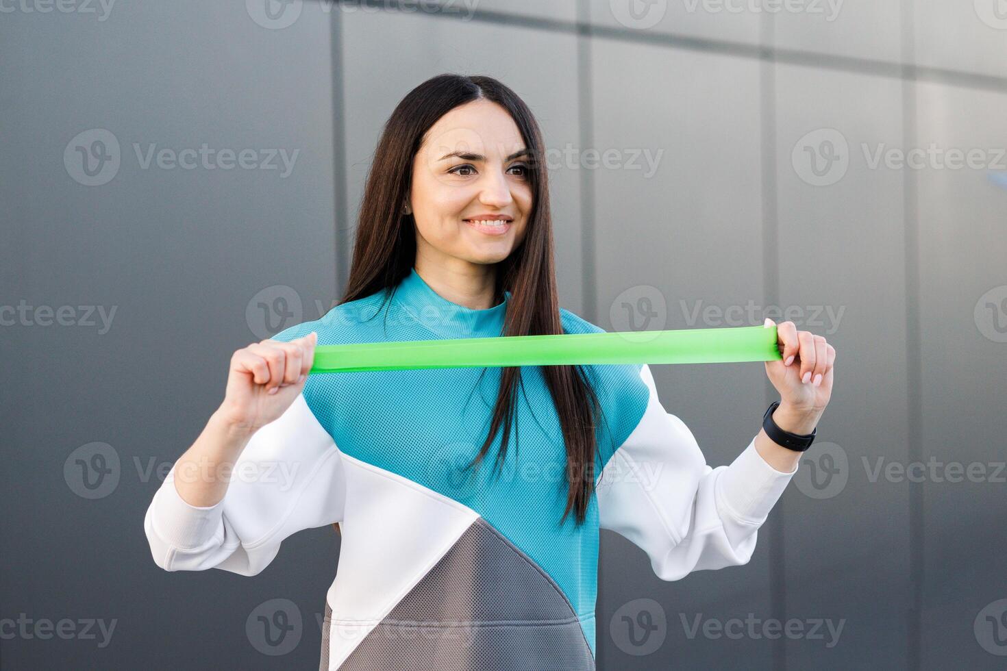 Fitness woman working with fitness rubber band outdoors. Fit girl training with rubber expander, healthy lifestyle concept photo