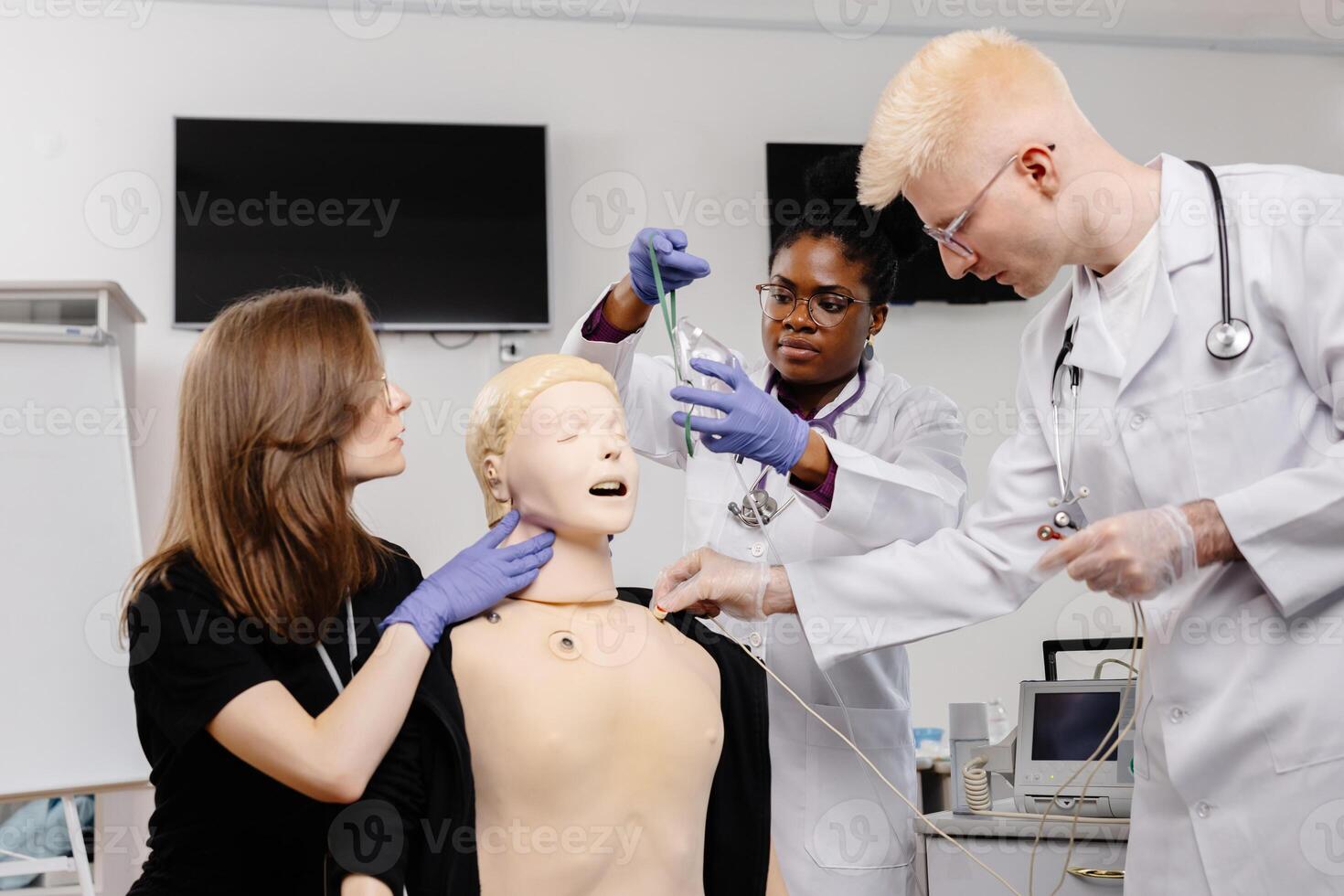Three medical students practice intubation on a mannequin in a classroom setting photo