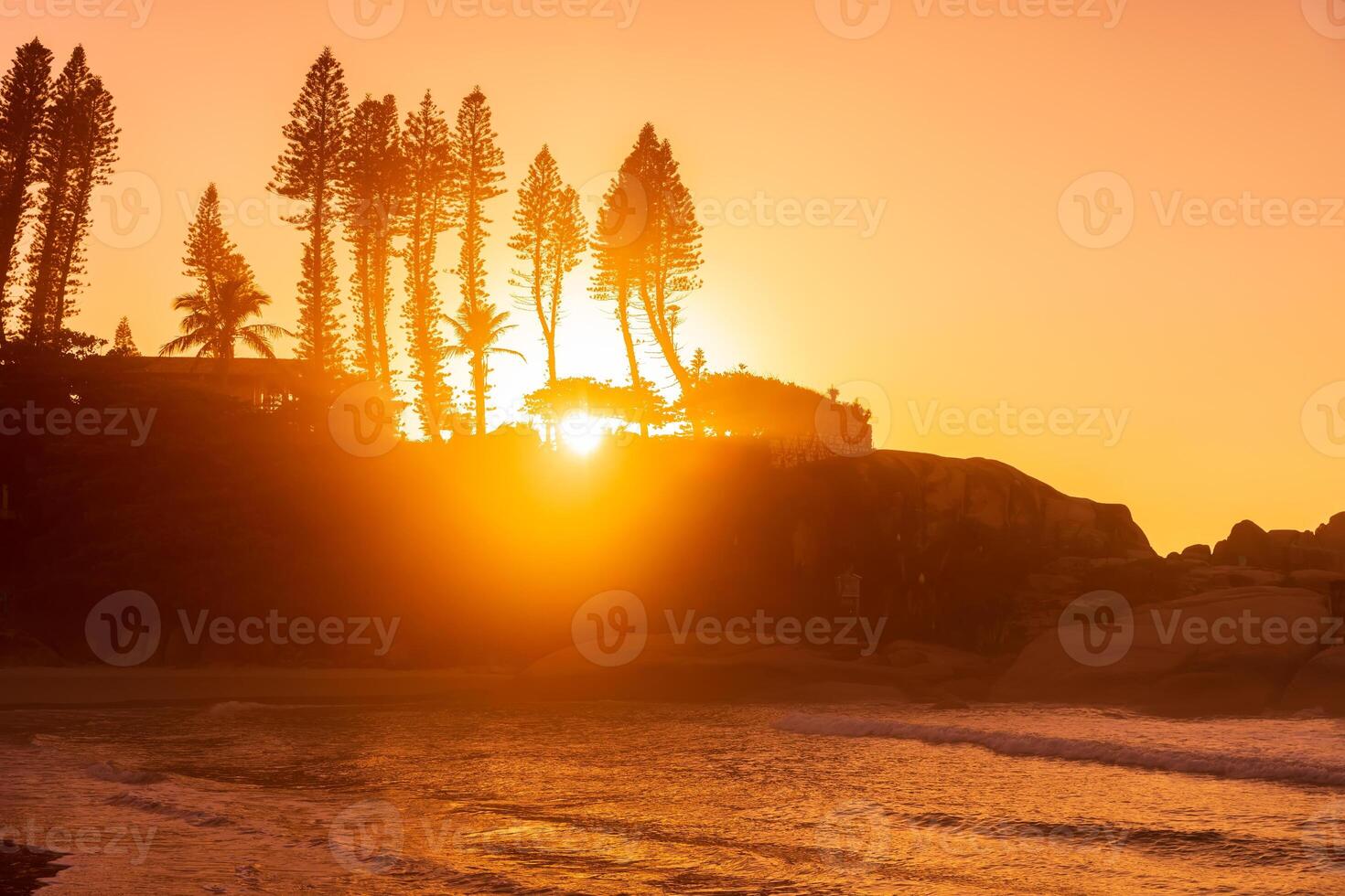 Sunrise on ocean beach with waves and rocks with trees. Beach in Brazil photo