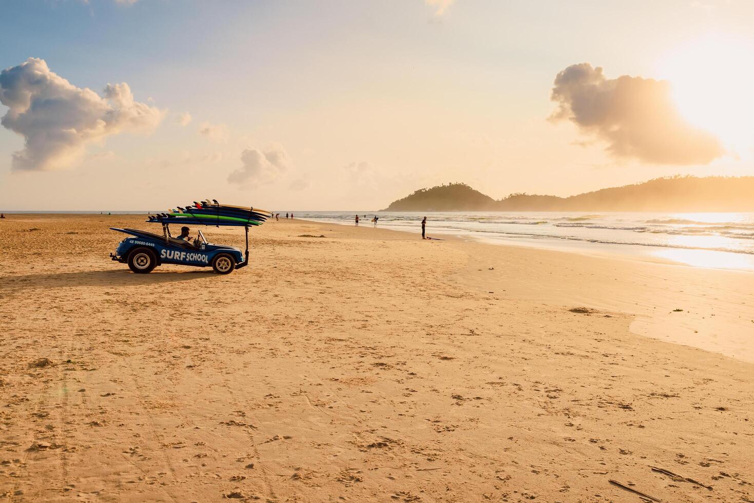 May 1, 2022. Florianopolis, Brazil. Beach with car of surf school and walking people on ocean with waves in Brazil. Morro das Pedras beach in Florianopolis photo
