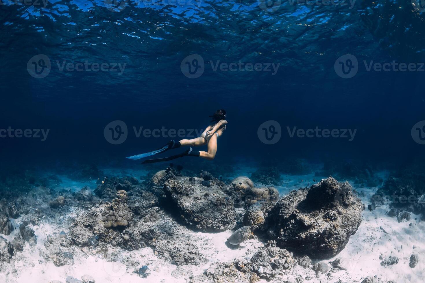 Woman freediver underwater in ocean. Freediving with fins in deep sea photo