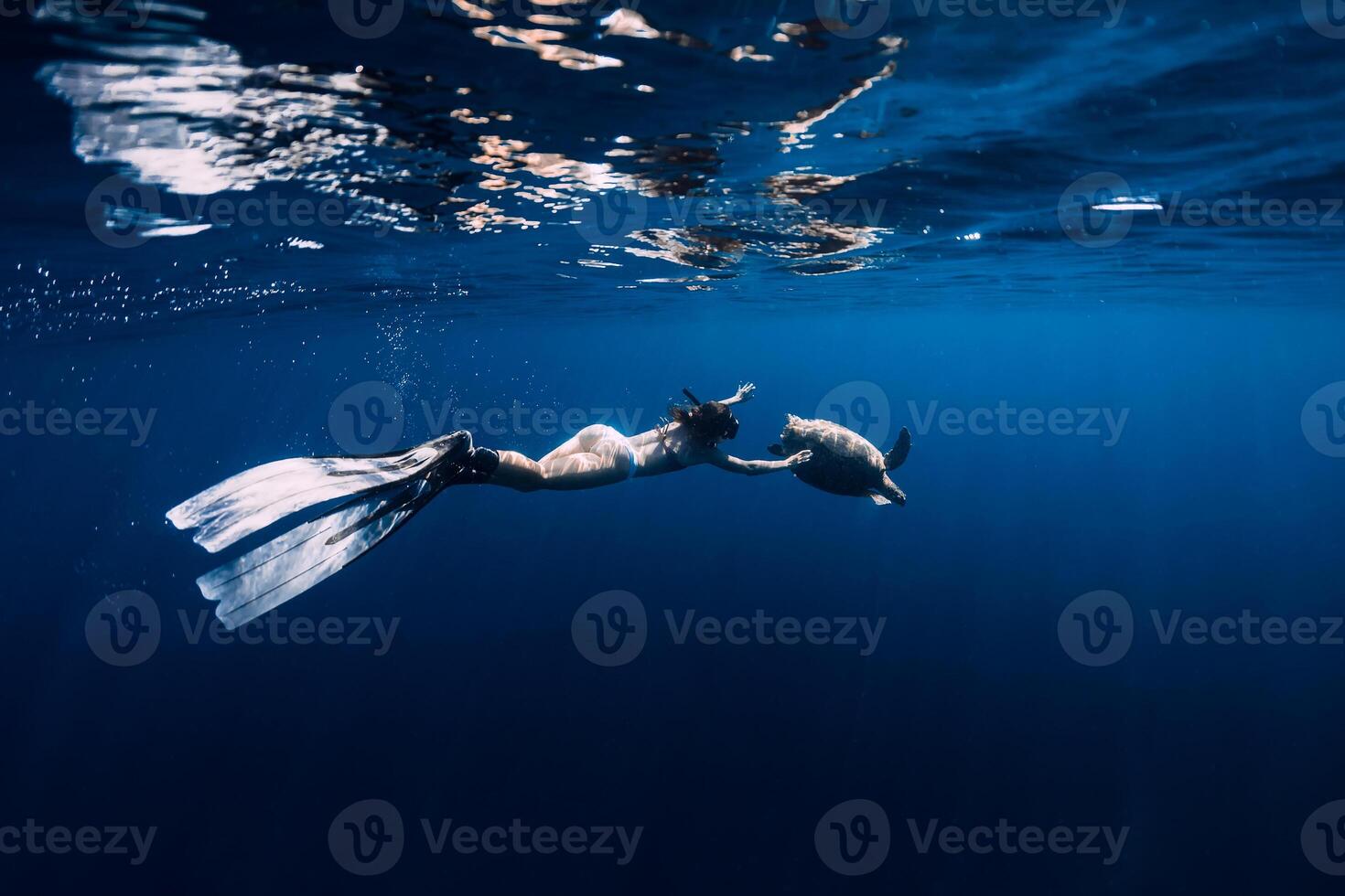 Snorkeling with sea turtle. Woman with fins swimming underwater with turtle. photo