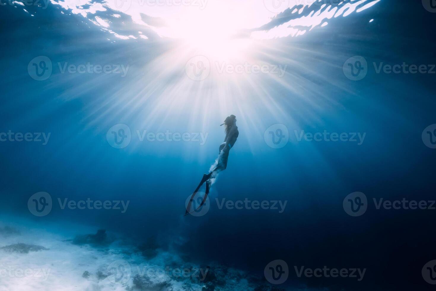 Freediver woman with fins swim underwater in sea. photo