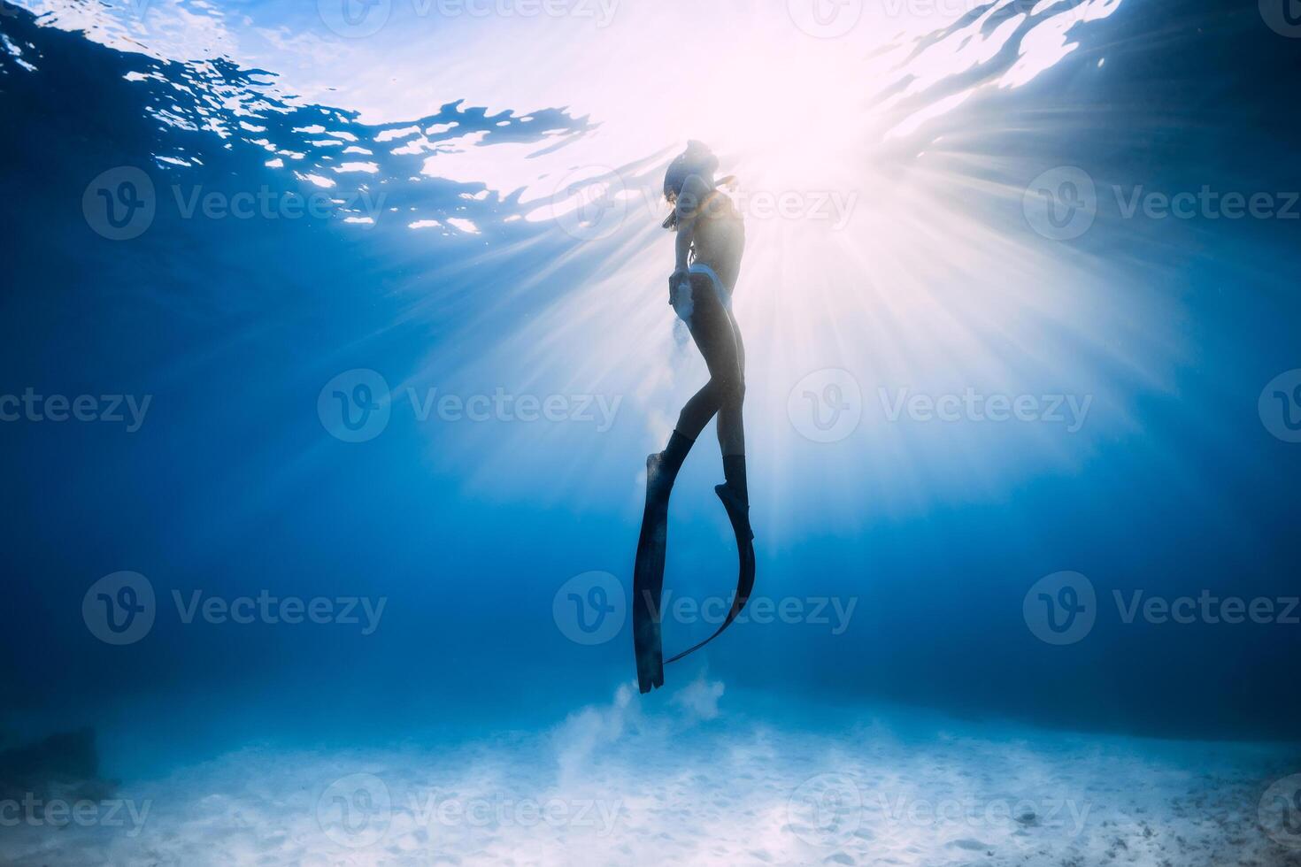 Freediver woman with fins swim underwater in sea. photo