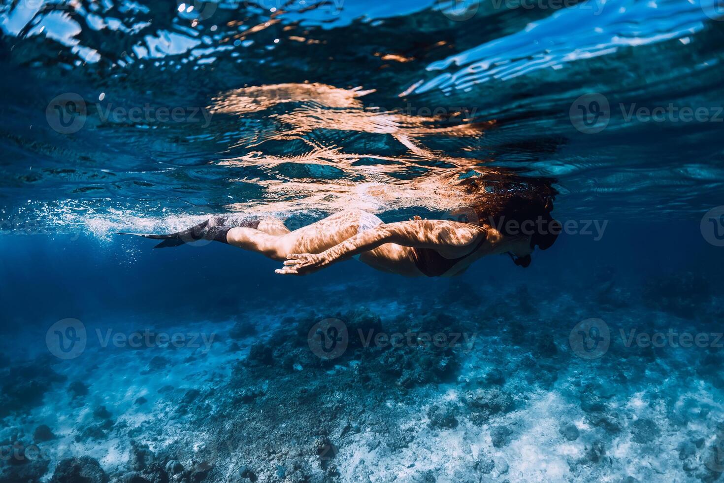 Woman freediver with fins dive in underwater ocean photo