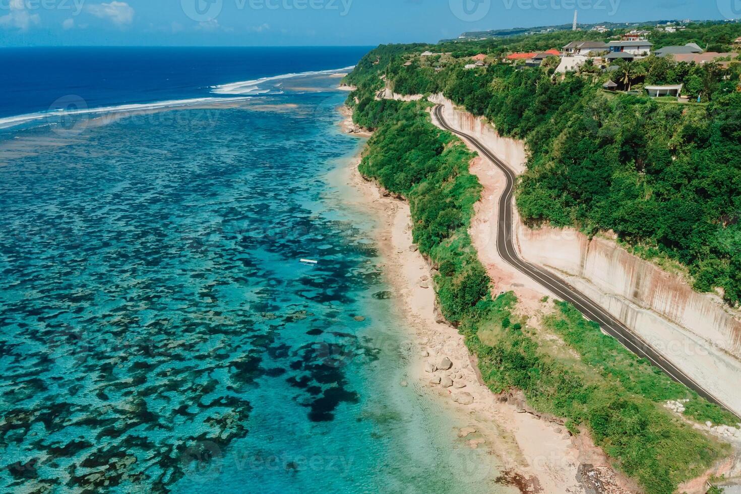 Beach under cliff with road. Coastline and turquoise ocean in Bali island. Aerial view photo