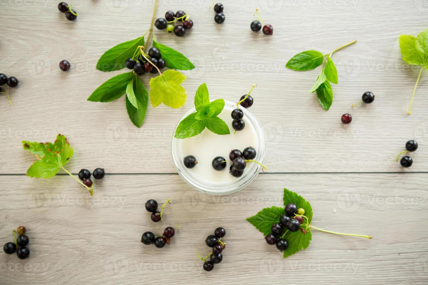 homemade sweet yogurt in a jar with black currants, on a wooden table photo