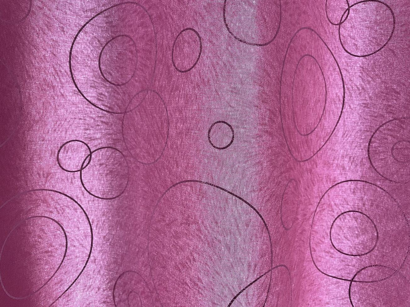 A pink fabric with a subtle sheen, decorated with an abstract pattern of black circles and ovals, creating a modern and elegant look. photo