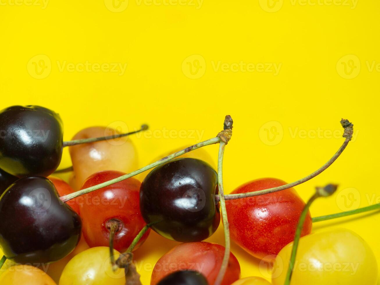 Sweet cherry with a stem on a yellow background. Bright table. Natural berries on the table. Harvest. Delicious food. photo