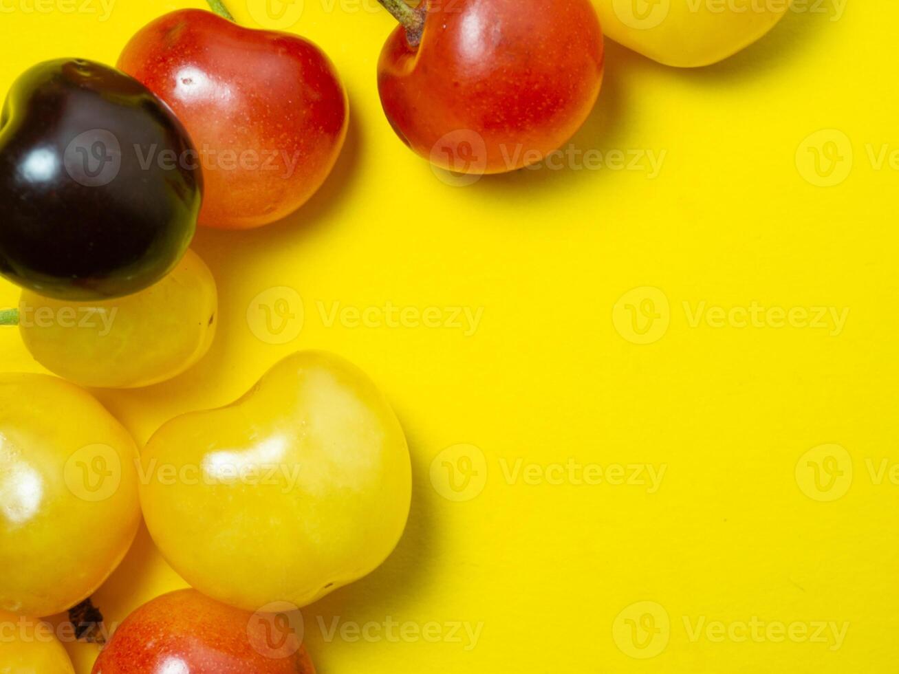 Sweet cherry with a stem on a yellow background. Bright table. Natural berries on the table. Cherries of different varieties. Place for an inscription photo