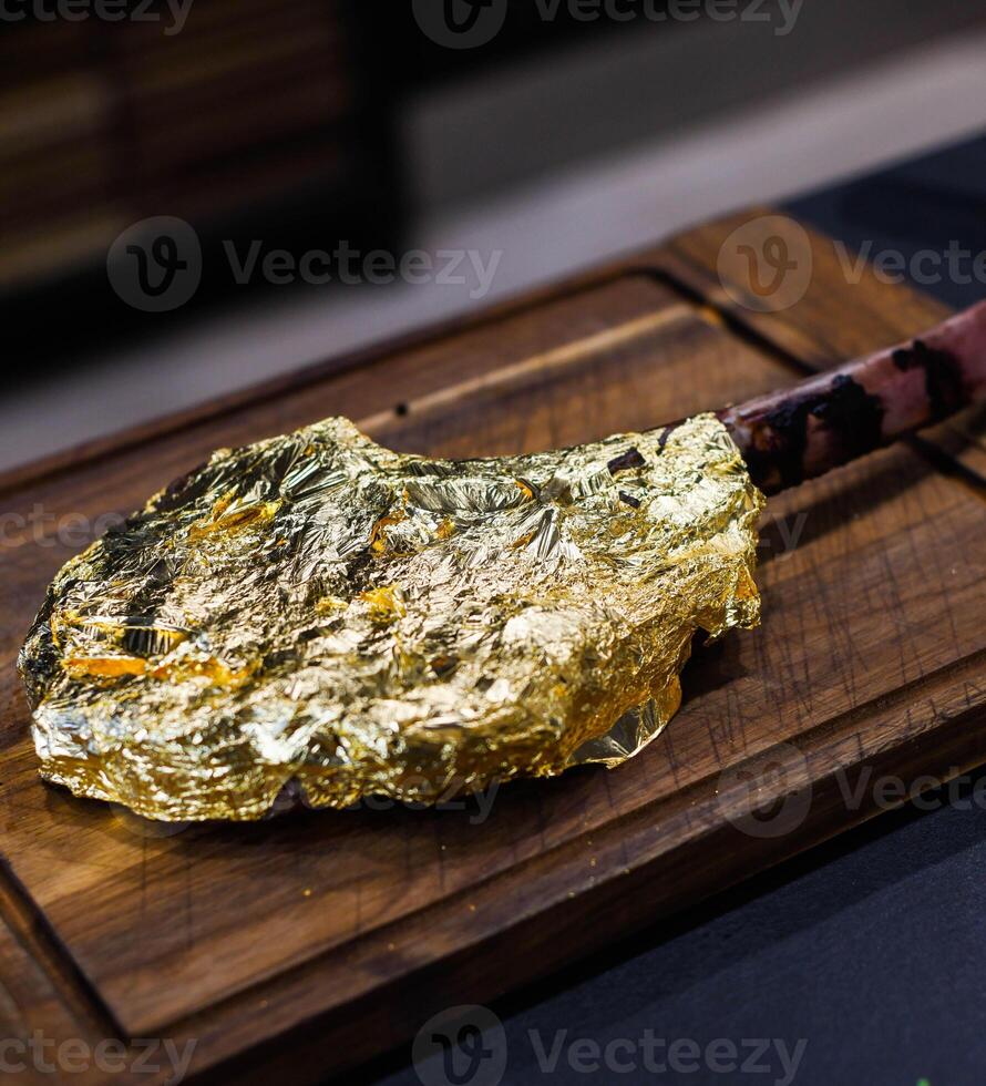 Premium beef tomahawk coated in edible gold photo