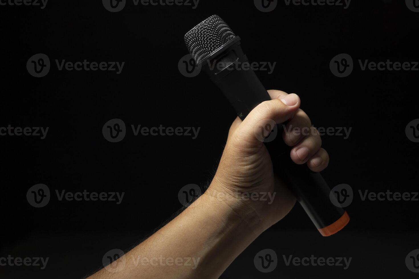 black microphone Male singer's hand holding microphone on modern singing stage On a black background and hands photo