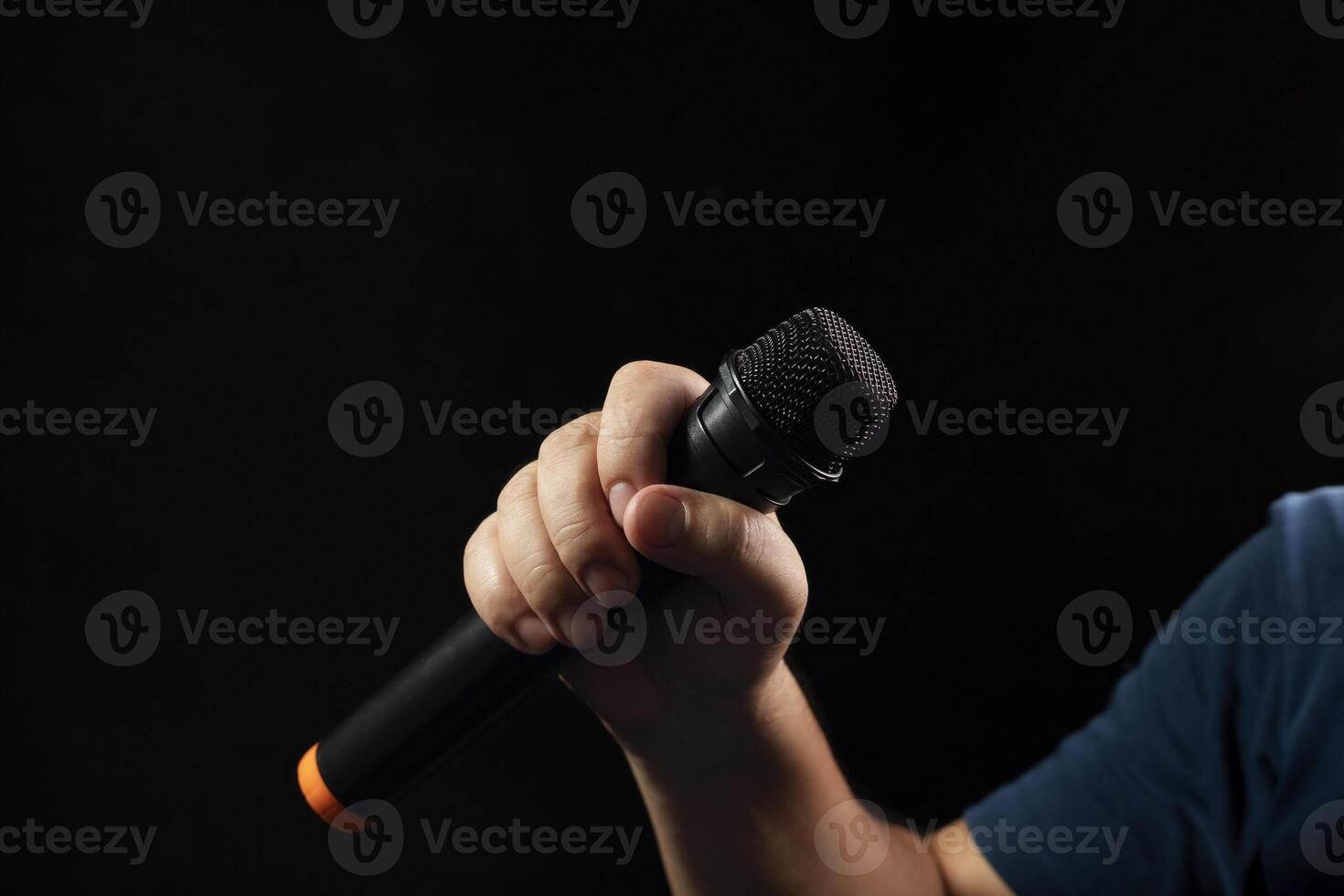 black microphone Male singer's hand holding microphone on modern singing stage On a black background and hands photo
