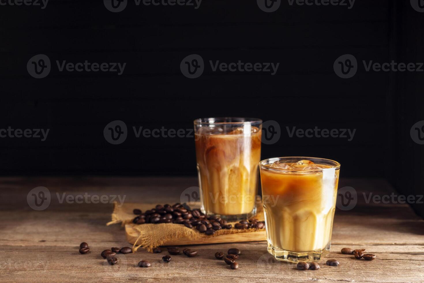 Soft iced coffee with milk, cream, white foam and ice. Coffee latte, espresso, cappuccino, cocktail ready to drink on dark and black background. photo