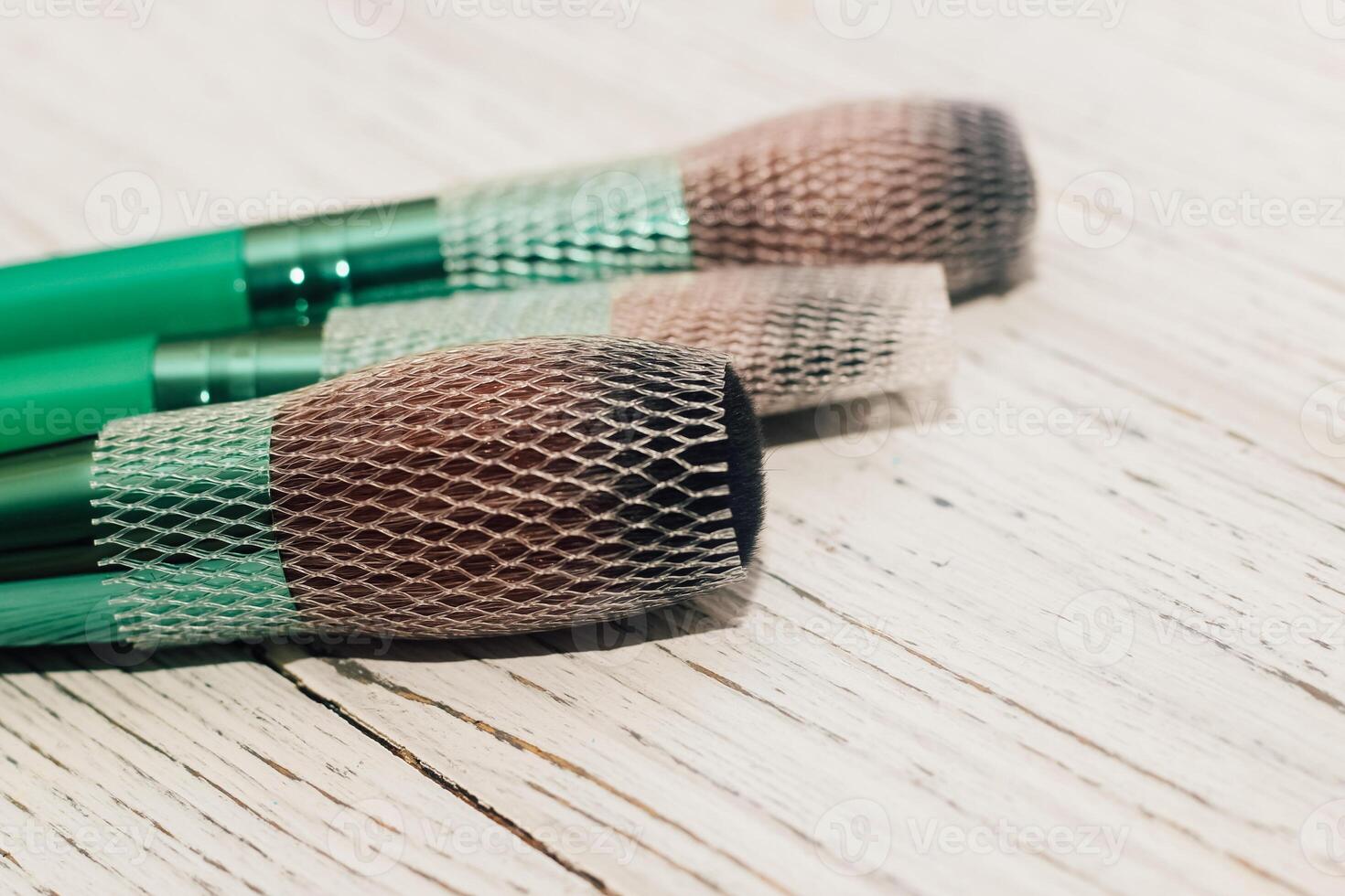 Green makeup brushes on a wooden table. photo