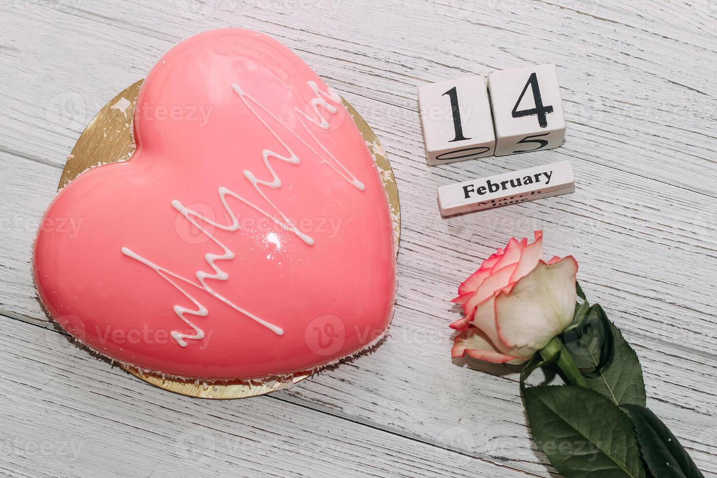 Pink tea rose with heart shaped pink mousse cake and February 14 calendar. photo