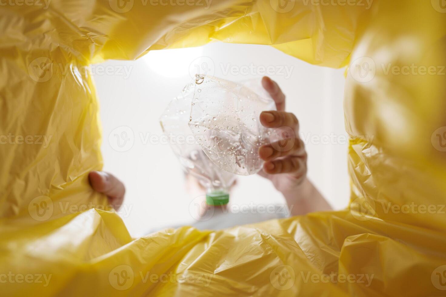 Image from inside yellow recycling bag of man throwing empty plastic bottle in recycling bin Home recycle eco green zero concept. photo