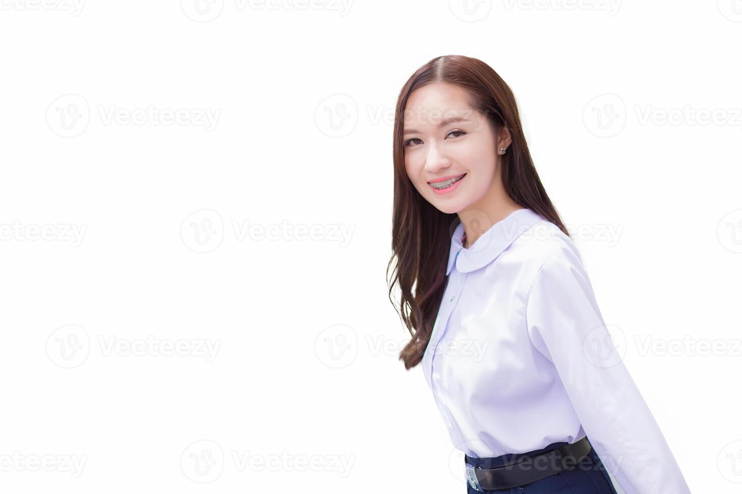Asian high school student in the school uniform with braces on her teeth stands and smiles confidently while she looks at the camera happily with the city while isolated white background. photo