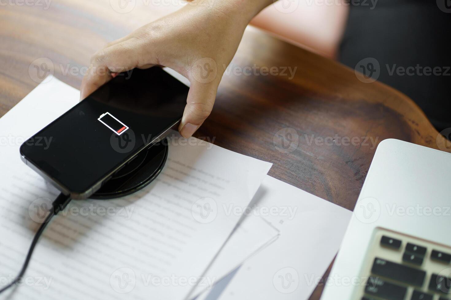 Charging mobile phone battery with wireless charging device in the table. Smartphone charging on a charging pad. Mobile phone near wireless charger Modern lifestyle technology concept photo