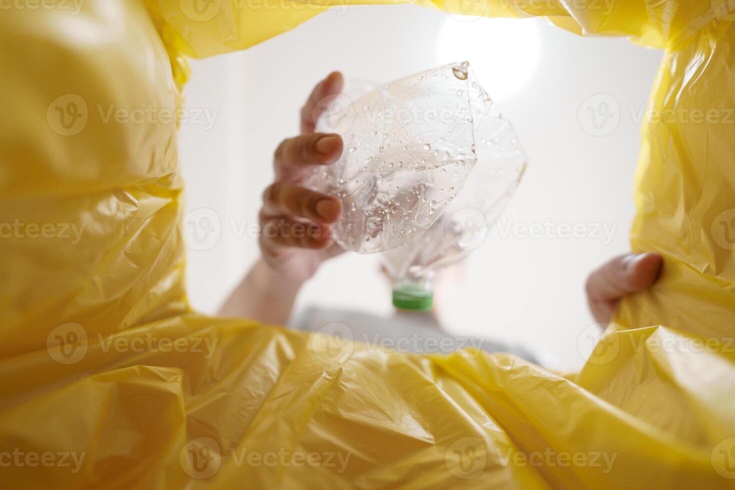Image from inside yellow recycling bag of man throwing empty plastic bottle in recycling bin Home recycle eco green zero concept. photo