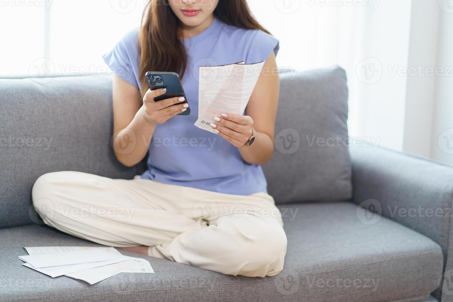 Asian woman holding paper document calculating money savings paying bills in mobile application using smart phone payment online with paying household bills tax insurance managing budget. photo
