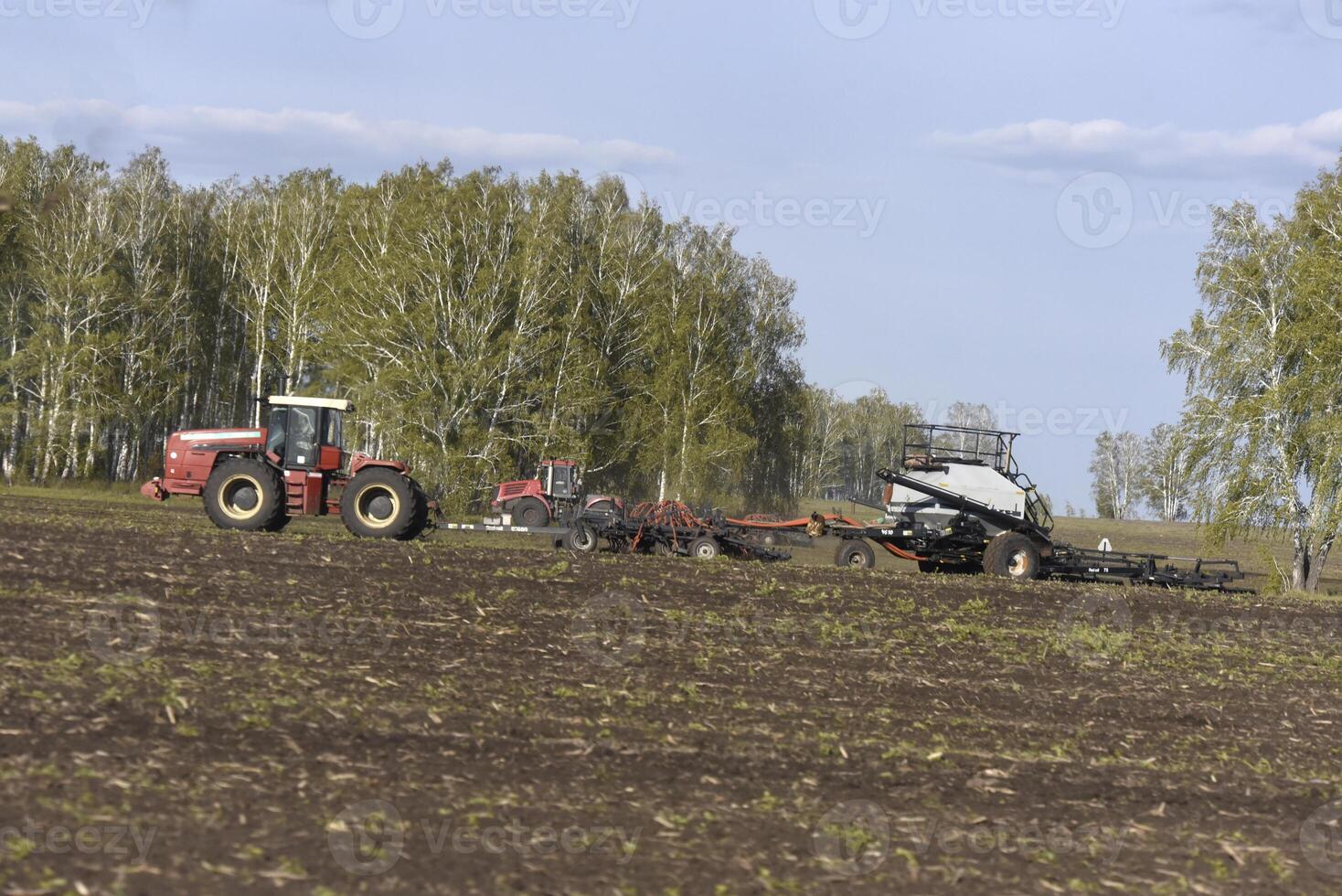 Agricultural machines for sowing grain in the field. Red tractors in the sowing campaign. photo