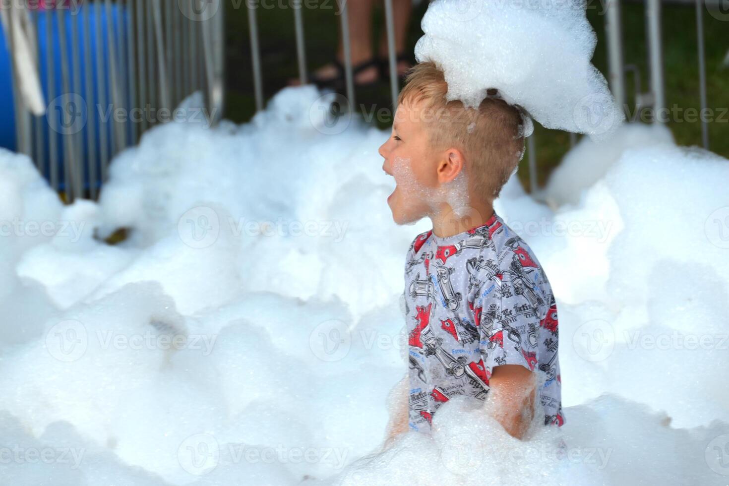 happy little boy with foam on his head, in wet clothes at a foam party photo