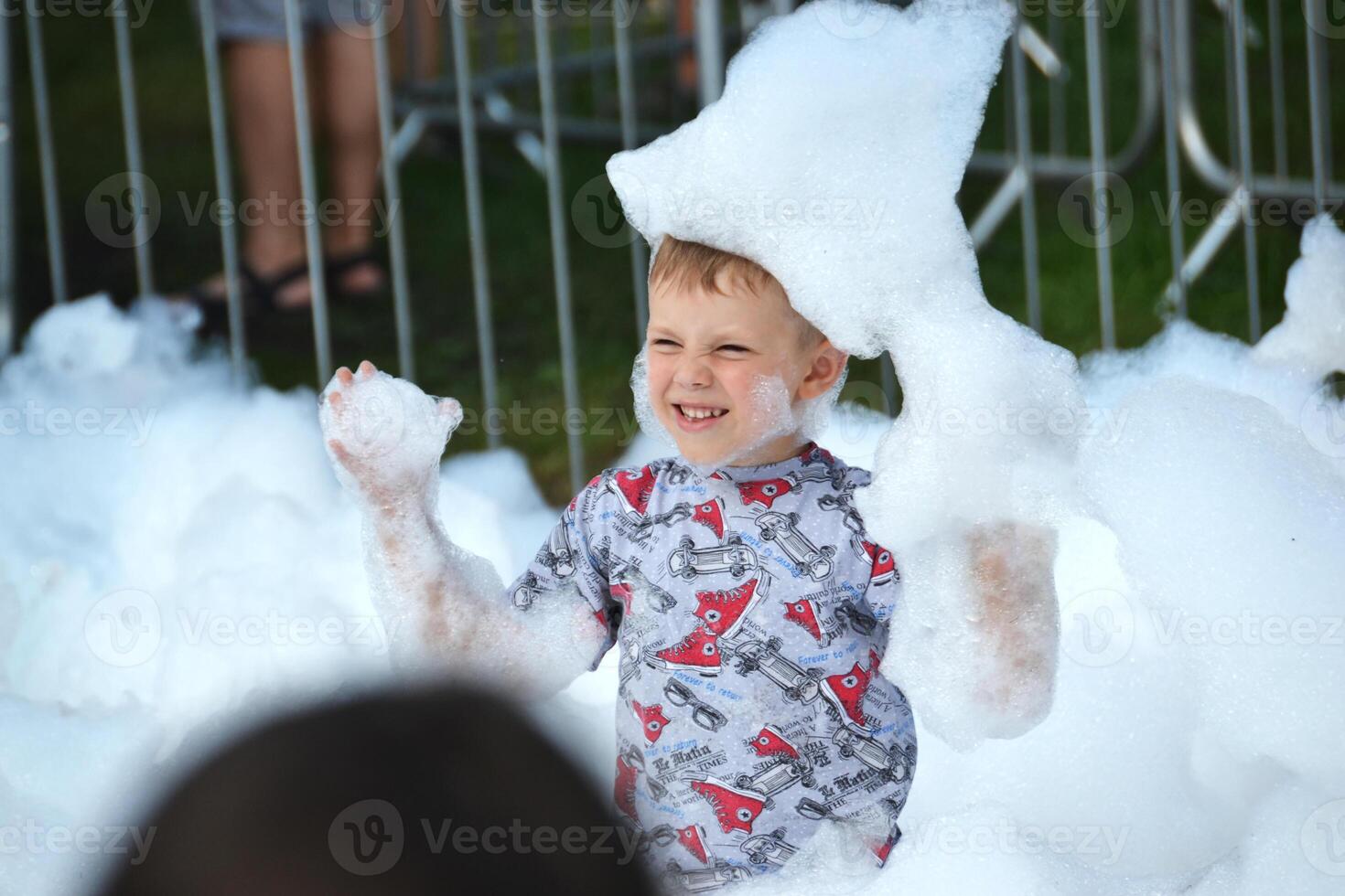 happy little boy with foam on his head, in wet clothes at a foam party photo