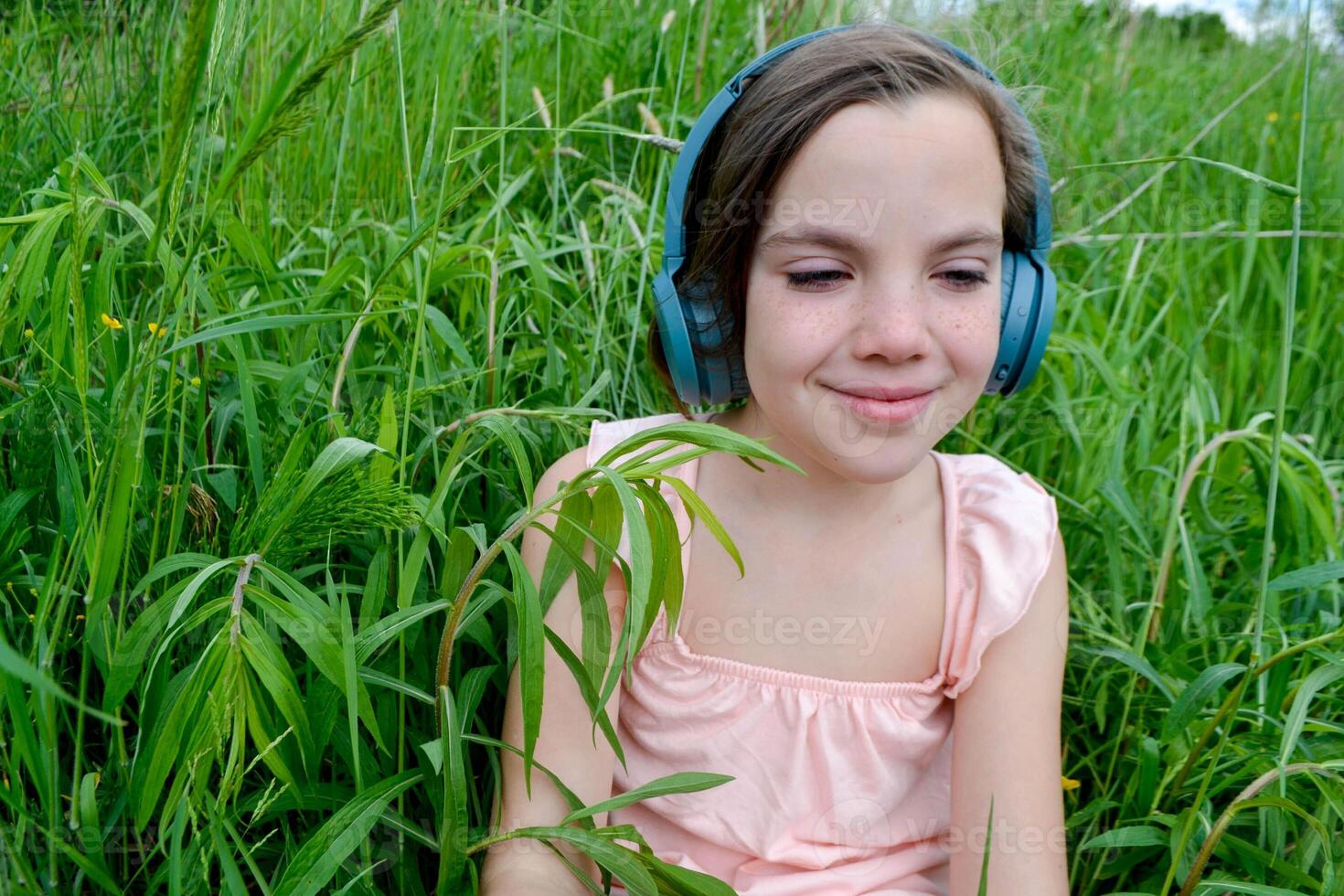 Relaxed woman lying on the grass listening to music with headphones in a park photo