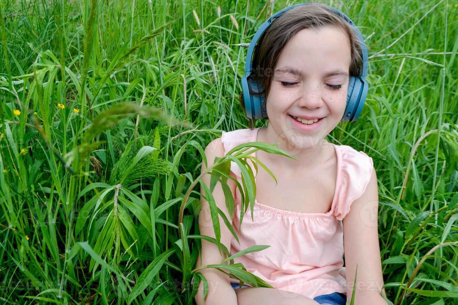 Relaxed woman lying on the grass listening to music with headphones in a park photo