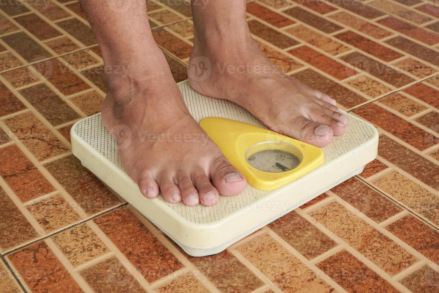 Close up of man legs standing on weight scales. Standing on floor scale at home. A man checking his weight photo