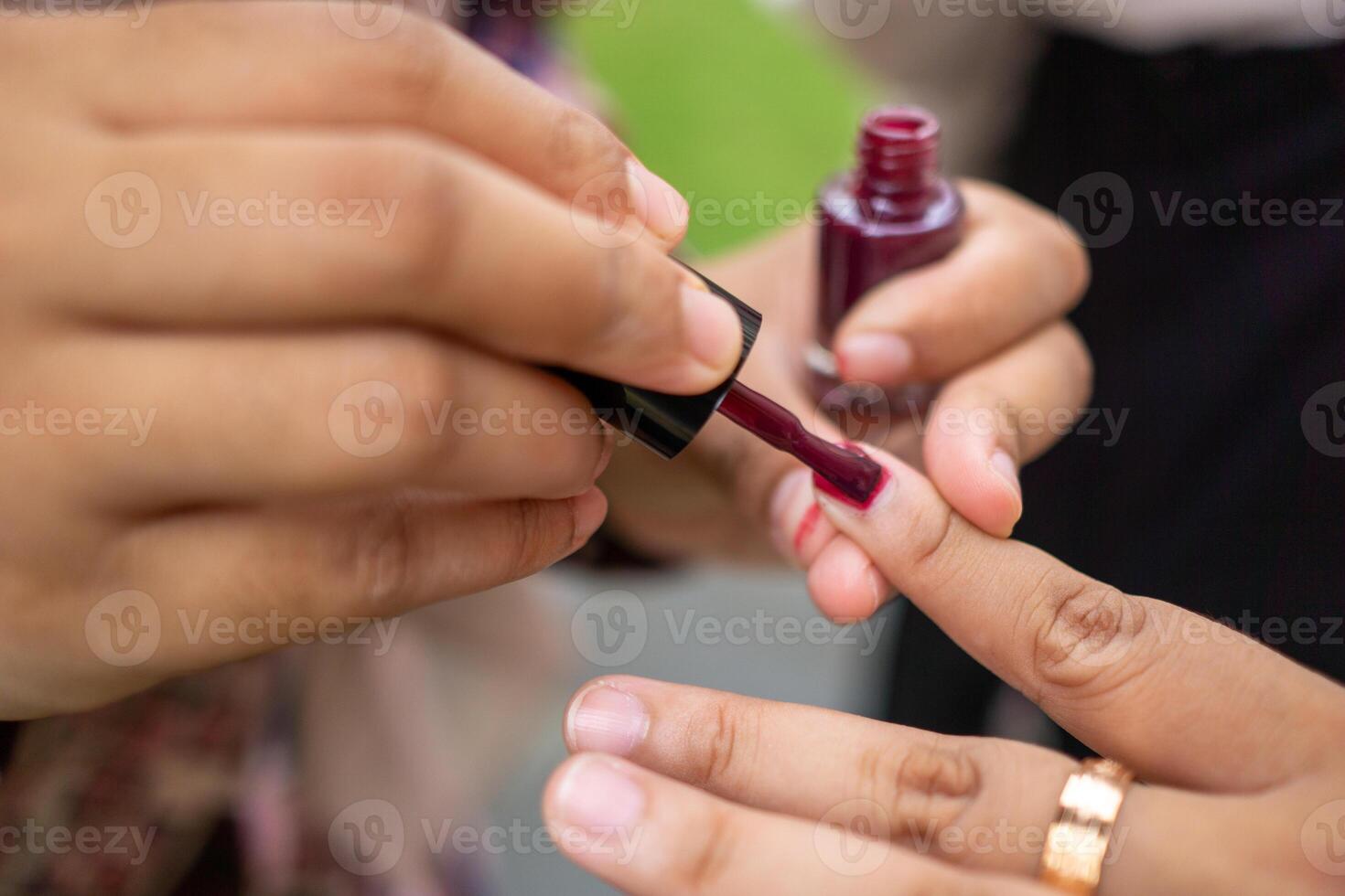 Image of Hands Putting Nail Color. Woman carefully applying nail polish on her friend nails. painting fingernails photo
