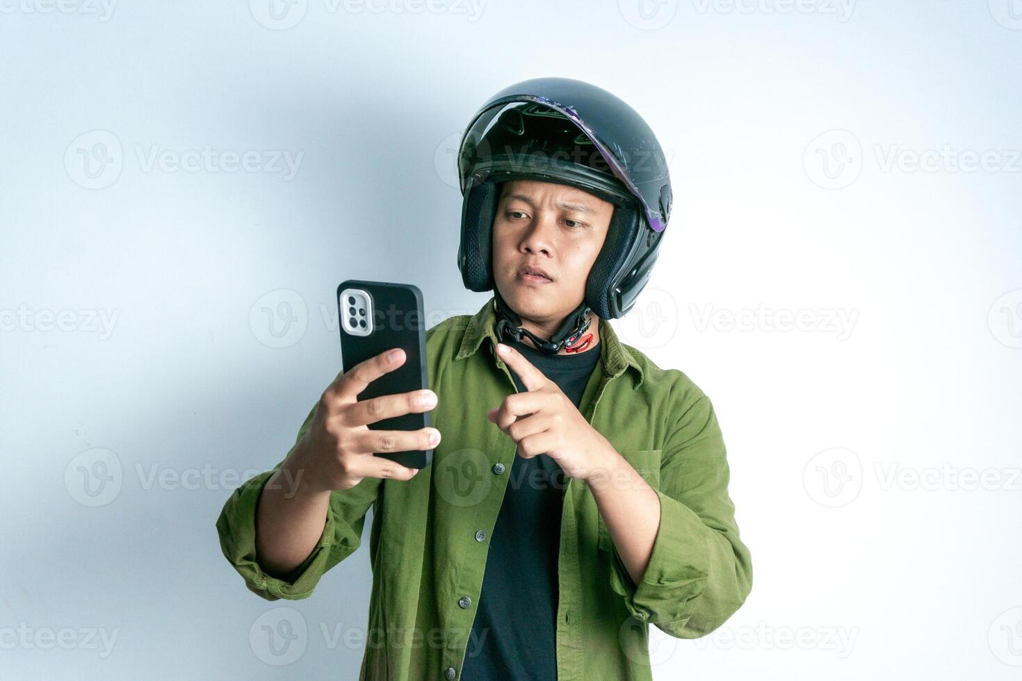 Adult Asian man confusing when looking to his handphone while wearing motorcycle helmet. Man looking to his phone with shocked expression photo
