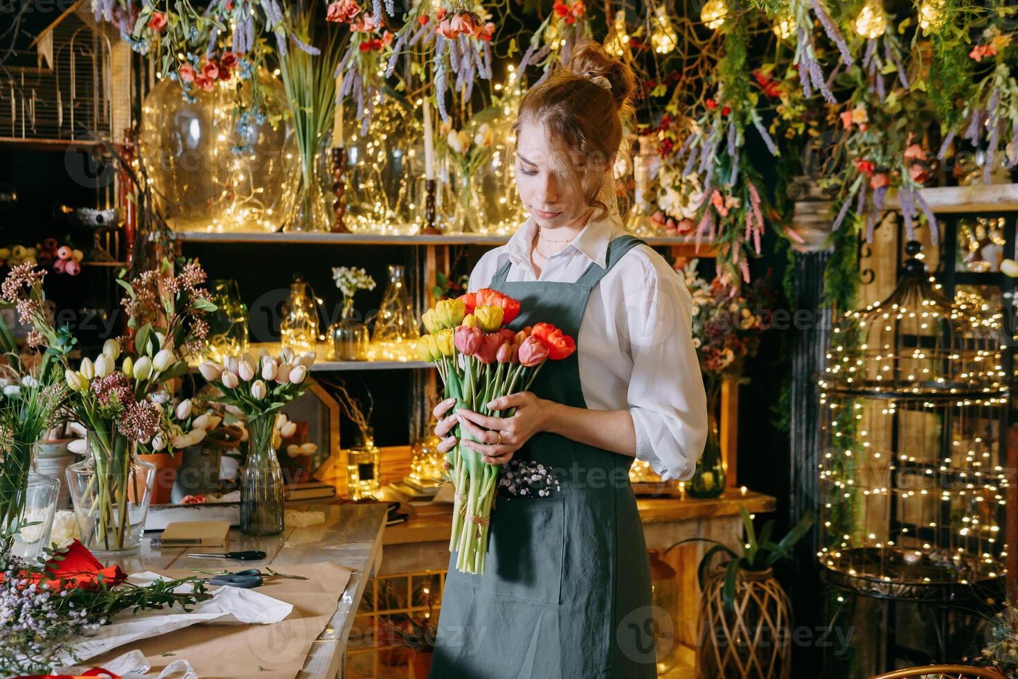 A woman in her florist shop collects bouquets of flowers. The concept of a small business. Bouquets of tulips for the holiday on March 8. photo