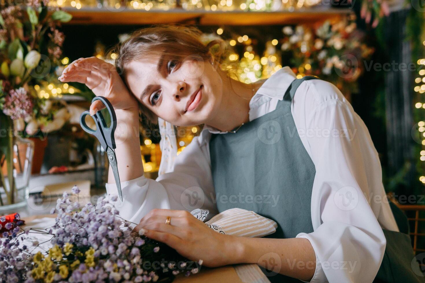 A woman in her florist shop collects bouquets of flowers. The concept of a small business. Bouquets of tulips for the holiday on March 8. photo