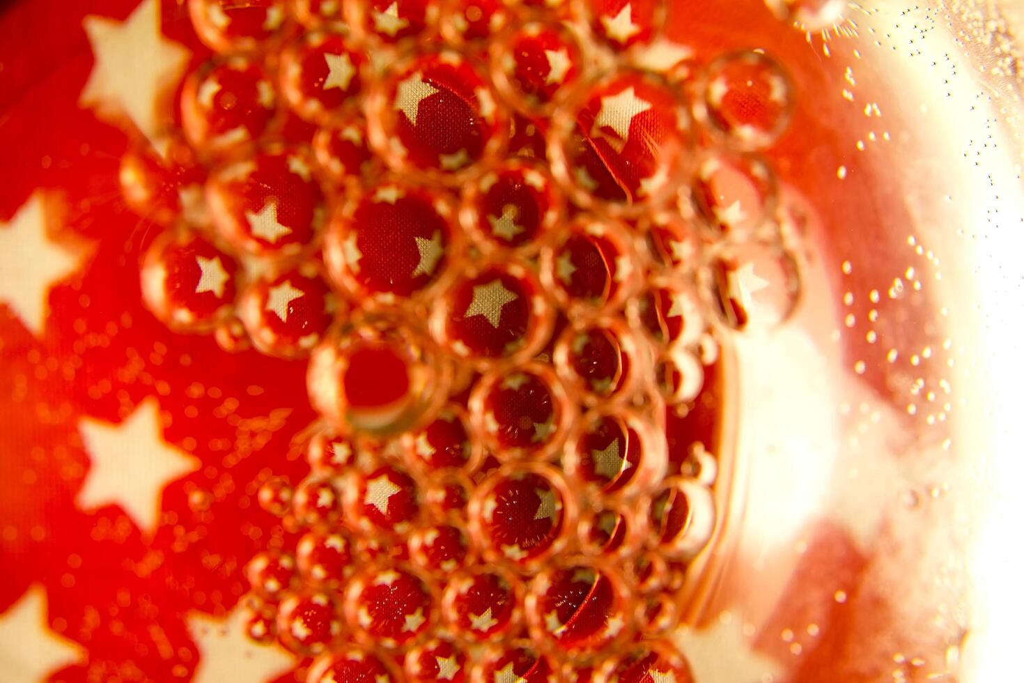 Red bubbles and drops of water on a white background star from an American flag. photo
