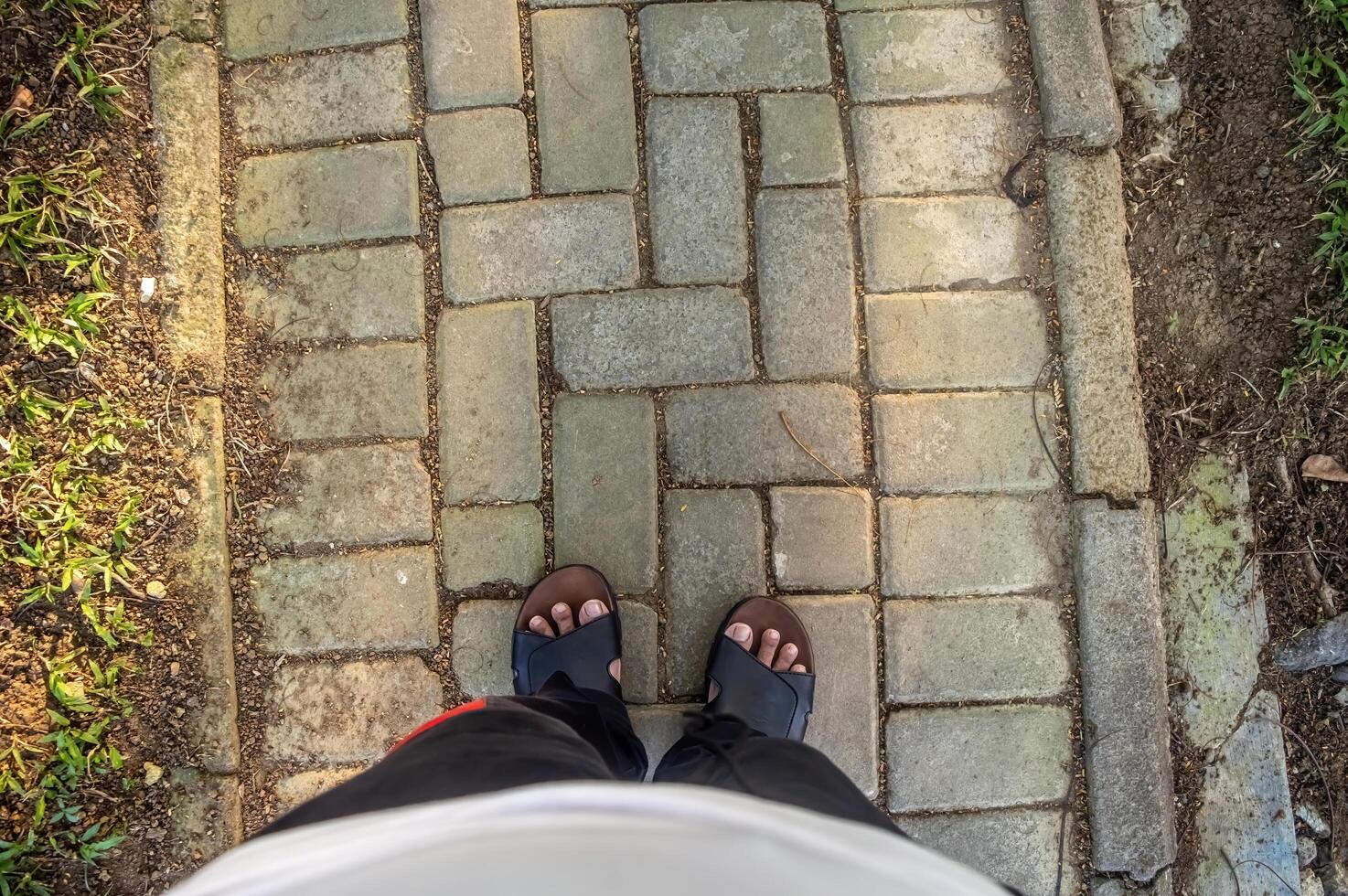 Man steps over a line on a paved surface. Looking down at a cobblestone street. photo