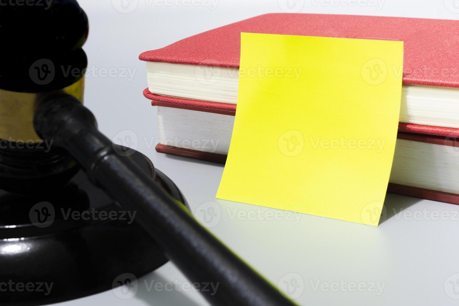 Judge's gavel with yellow note and red books on white background. photo
